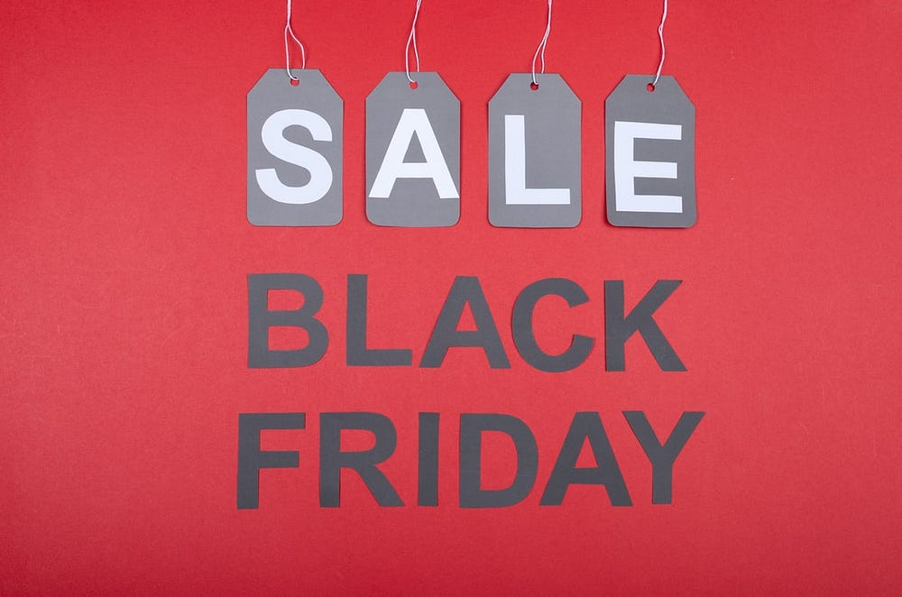 Three gray tags with the letters "SALE" hanging against a red background with the words "BLACK FRIDAY" displayed below.