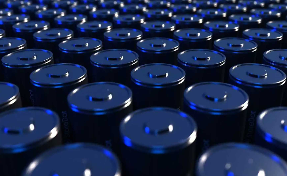 A vast array of cylindrical blue batteries closely packed together, with a focus on their positive terminals.