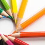 Colorful pencils in sunburst pattern, vibrant hues on white background for creative inspiration.