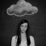 Serene woman standing with raincloud symbolizing introspection and emotional weight.