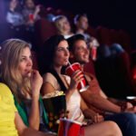 Group watching film at cinema, engrossed in classic movie theater experience.