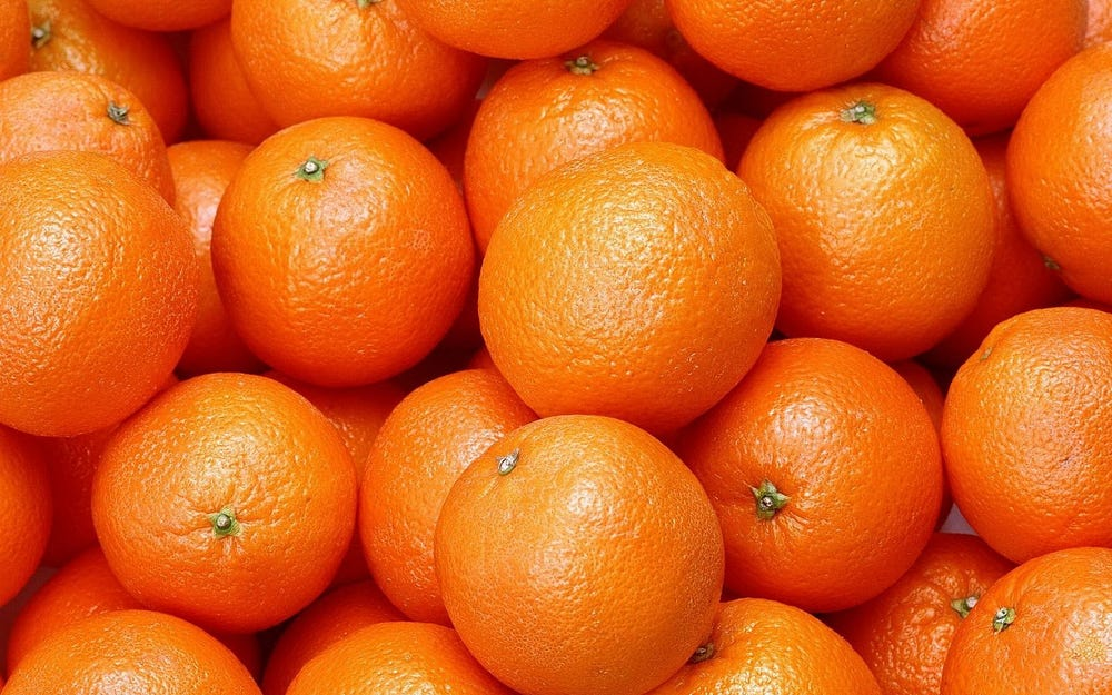 Close-up of multiple fresh, ripe oranges filling the frame.