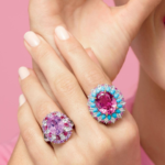 Radiant gemstone rings and joyful smile on soft pink background.
