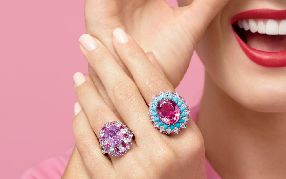 Radiant gemstone rings and joyful smile on soft pink background.