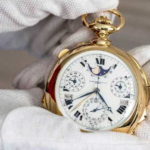 Luxury gold pocket watch with intricate details held by white-gloved hands.