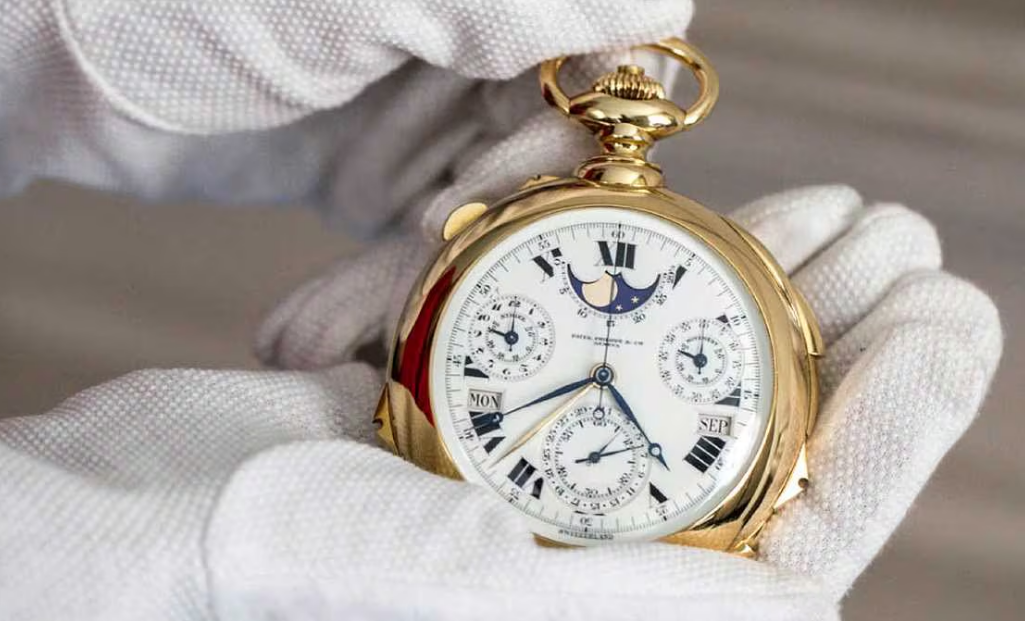 Luxury gold pocket watch with intricate details held by white-gloved hands.