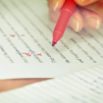 Hand editing document with red pen, focusing on corrections and annotations.