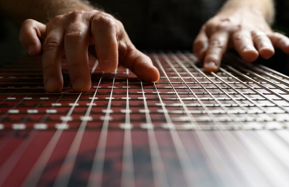 Person adjusting faders on digital mixing board in studio setting with dramatic lighting.