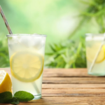 Refreshing lemonade drinks on wooden table with mint and lemon slices, outdoor relaxation vibe.
