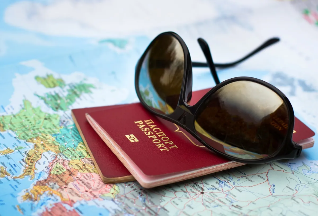 A pair of sunglasses resting on a red passport, which lies on top of a map featuring Europe.