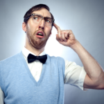 Quirky man in glasses and bow tie looking puzzled against gradient grey background.