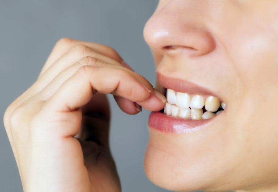 Close-up of person biting nail in thoughtful gesture, displaying signs of anxiety or nervousness.