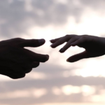 Reaching hands symbolize human connection and diversity against a tranquil dawn sky.