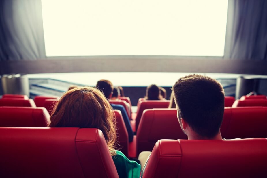 Empty cinema theater with red seats and blank screen, creating a cozy and cinematic atmosphere.