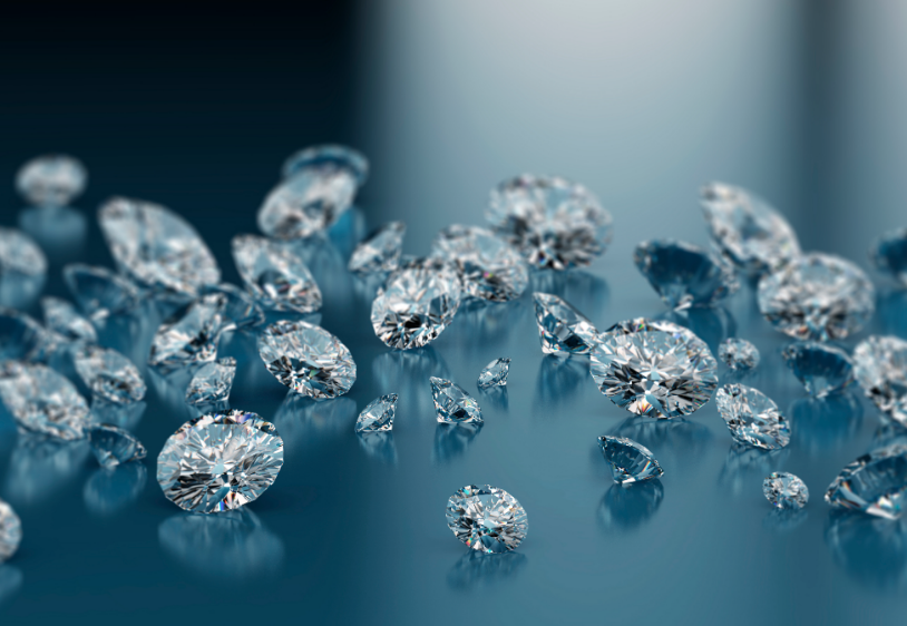 Multiple cut diamonds scattered on a reflective blue surface with soft-focus background.