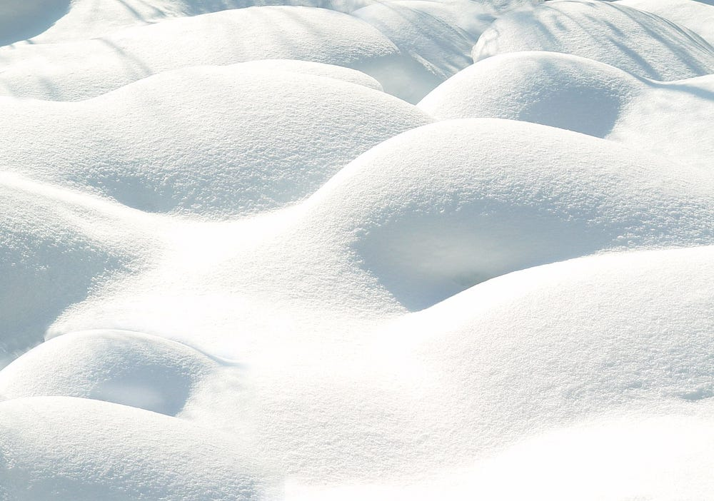 Undulating snow drifts with soft shadows, showcasing the texture of a snow-covered landscape.