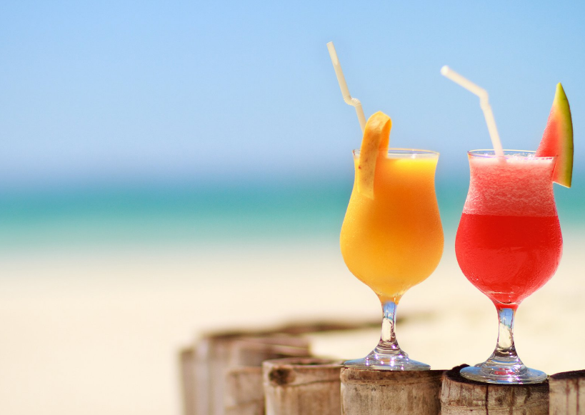 Enjoy tropical cocktails by the beach: vibrant colors, fruit garnishes, and straw sips.