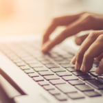 Person typing on laptop keyboard in warm light, showcasing focused productivity.