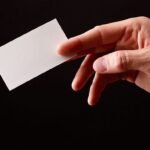 Hand presenting blank business card for professional networking and formal introductions.
