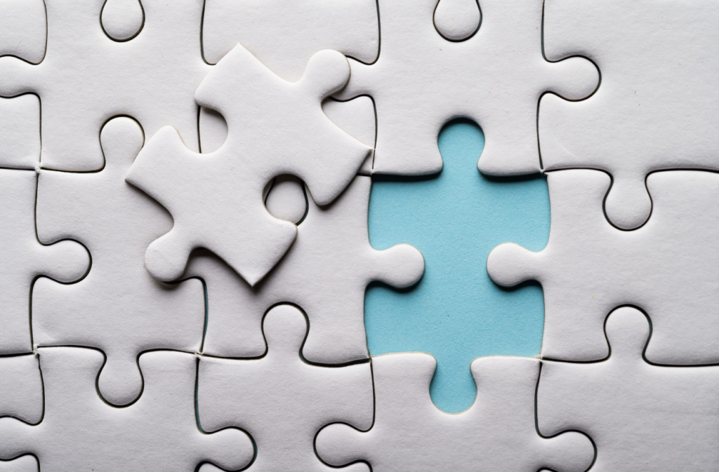 A white jigsaw puzzle with one piece missing, revealing a blue background beneath.