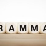 Wooden blocks spelling GRAMMAR in black letters on smooth surface, educational language image.