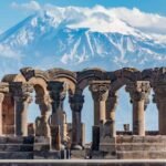 Ancient stone columns with Mount Ararat in the background under a clear blue sky.