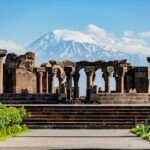 Ancient ruins with ornate columns against majestic Mount Ararat, showcasing historical and natural beauty.