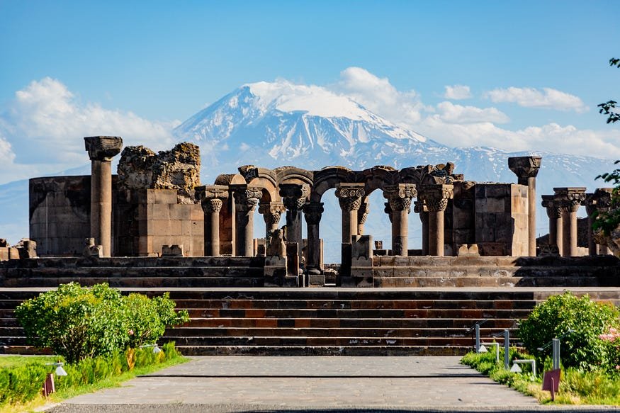 Ancient ruins with ornate columns against majestic Mount Ararat, showcasing historical and natural beauty.