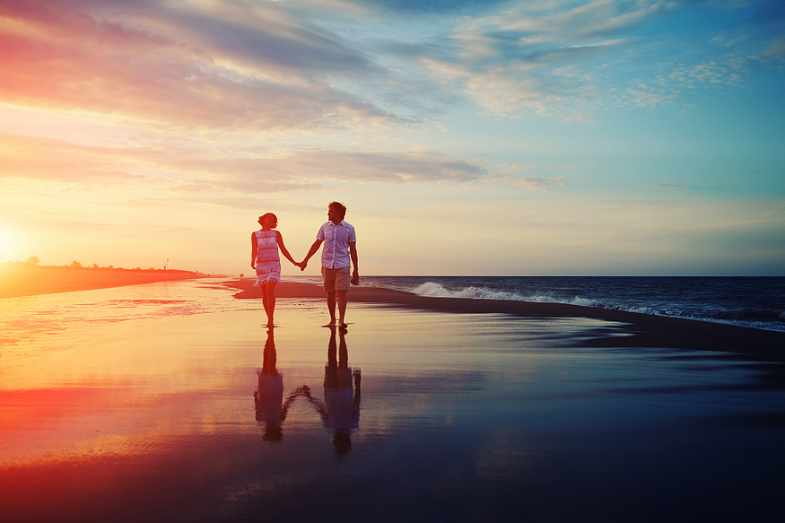 Sunset stroll on peaceful beach with reflections, creating serene and intimate atmosphere.