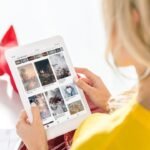 Blonde woman browsing social media for inspiring photos on tablet.