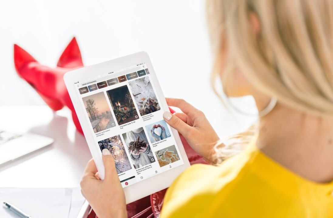 Blonde woman browsing social media for inspiring photos on tablet.