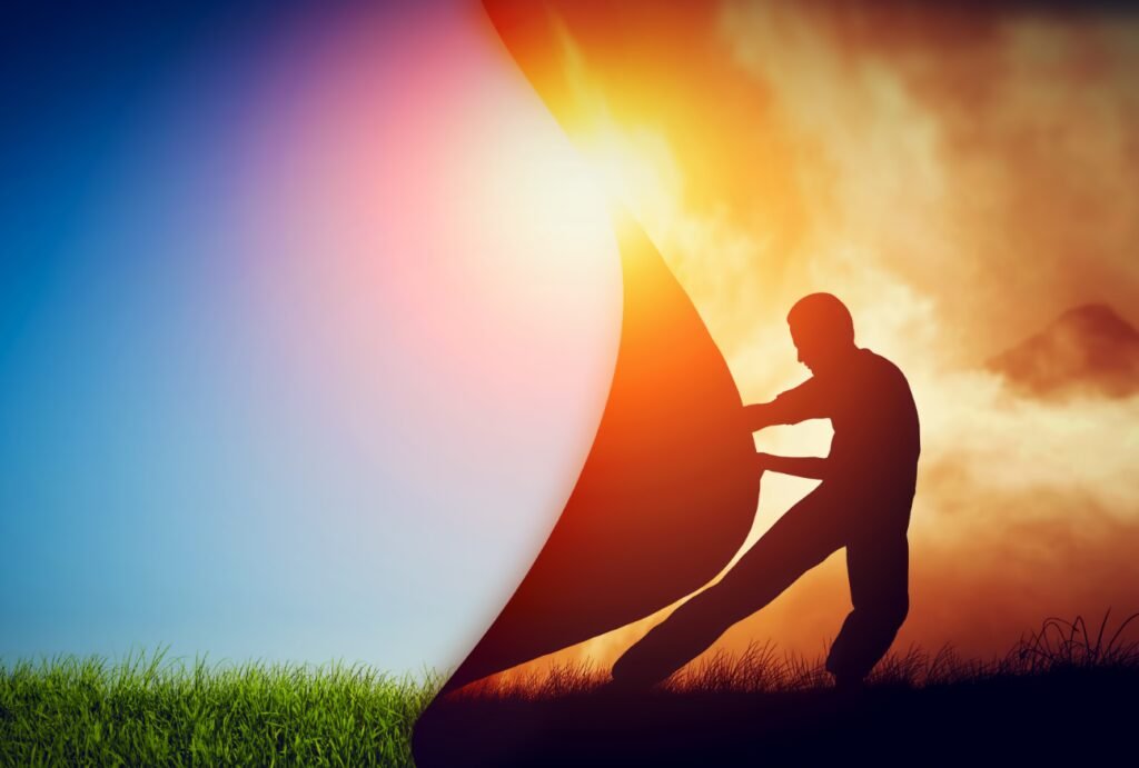 Silhouette of a person peeling back a dark layer to reveal a bright, colorful scene underneath, divided by a straight line.