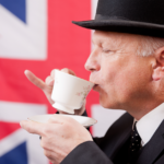 Sophisticated person drinking tea with Union Jack backdrop evoking British tradition.