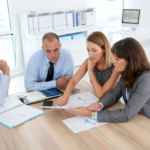 Business professionals in a modern office discussing documents and digital tablet.