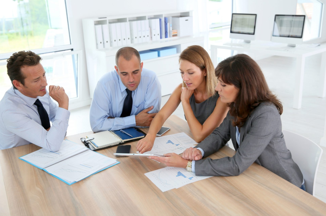 Business professionals in a modern office discussing documents and digital tablet.