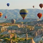 Colorful hot air balloons float over Cappadocias fairy chimneys at sunrise, creating a picturesque scene.