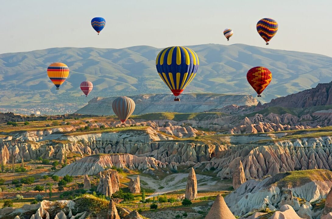 Colorful hot air balloons float over Cappadocias fairy chimneys at sunrise, creating a picturesque scene.