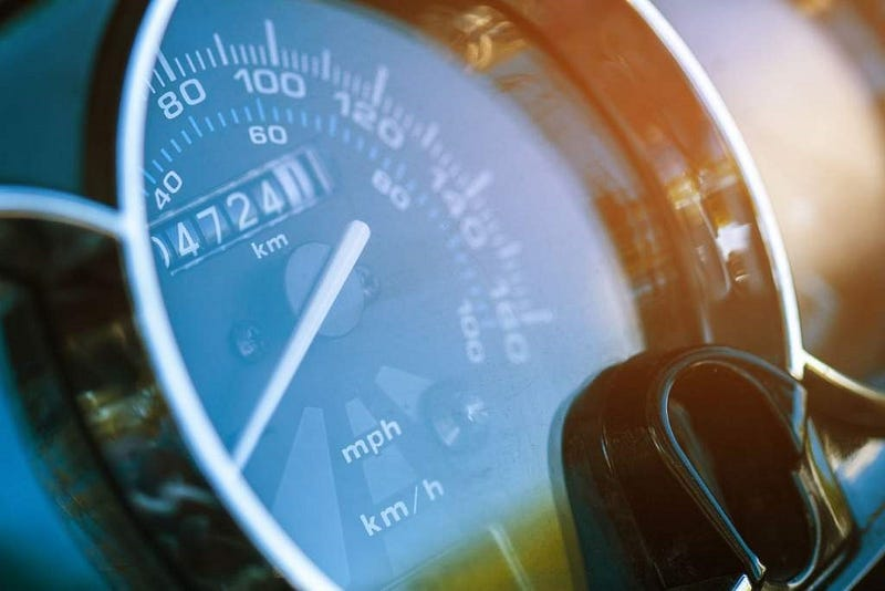 Close-up of a car speedometer with a needle pointing to zero and odometer reading 472411 km, with blue tint and reflective light.