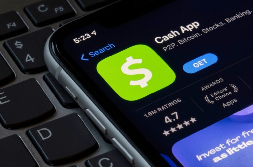 Smartphone displaying the Cash App in an app store with a rating of 4.7 stars, placed on a keyboard.