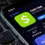 Cash App on iPhone displayed on sleek keyboard, creating modern workspace vibe.