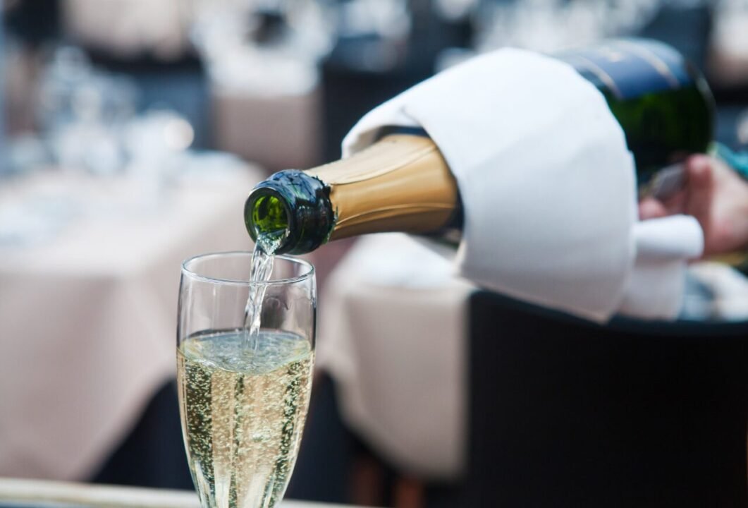 Champagne being poured into a glass at an elegantly set table.