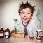 Child conducting vibrant science experiment with chemicals and test tubes on table.