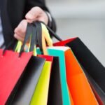 Brightly colored shopping bags held by hand, suggesting a vibrant shopping experience.