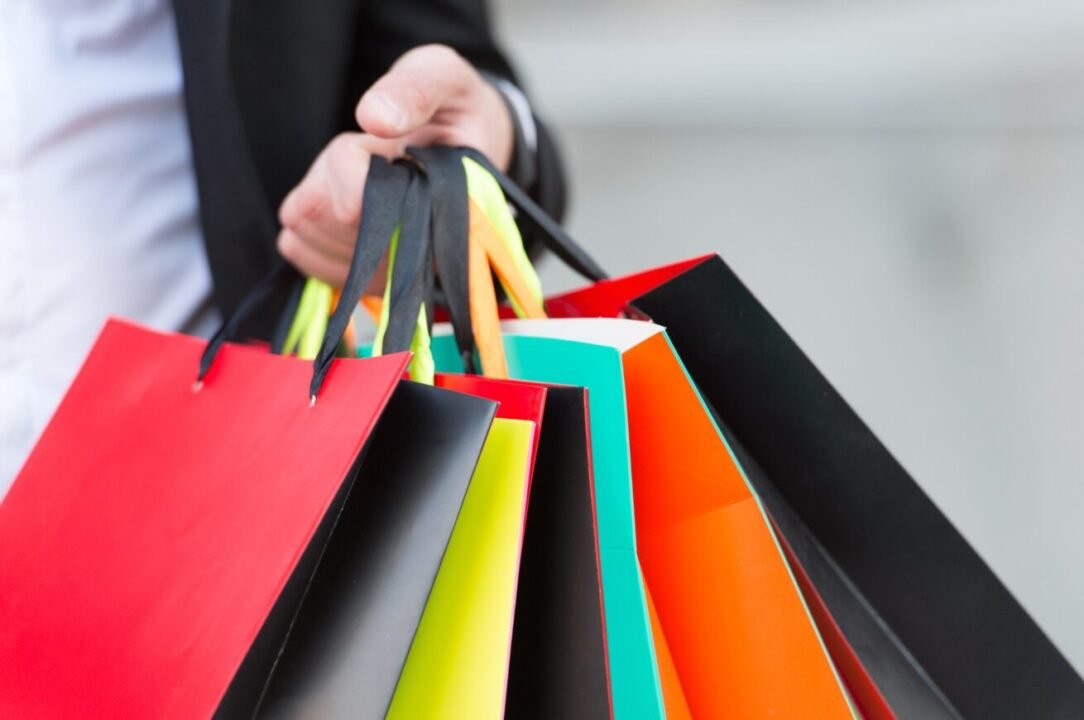 Brightly colored shopping bags held by hand, suggesting a vibrant shopping experience.