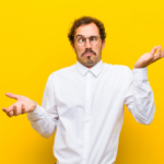 Confused man in white shirt against vibrant yellow background, expressing uncertainty.