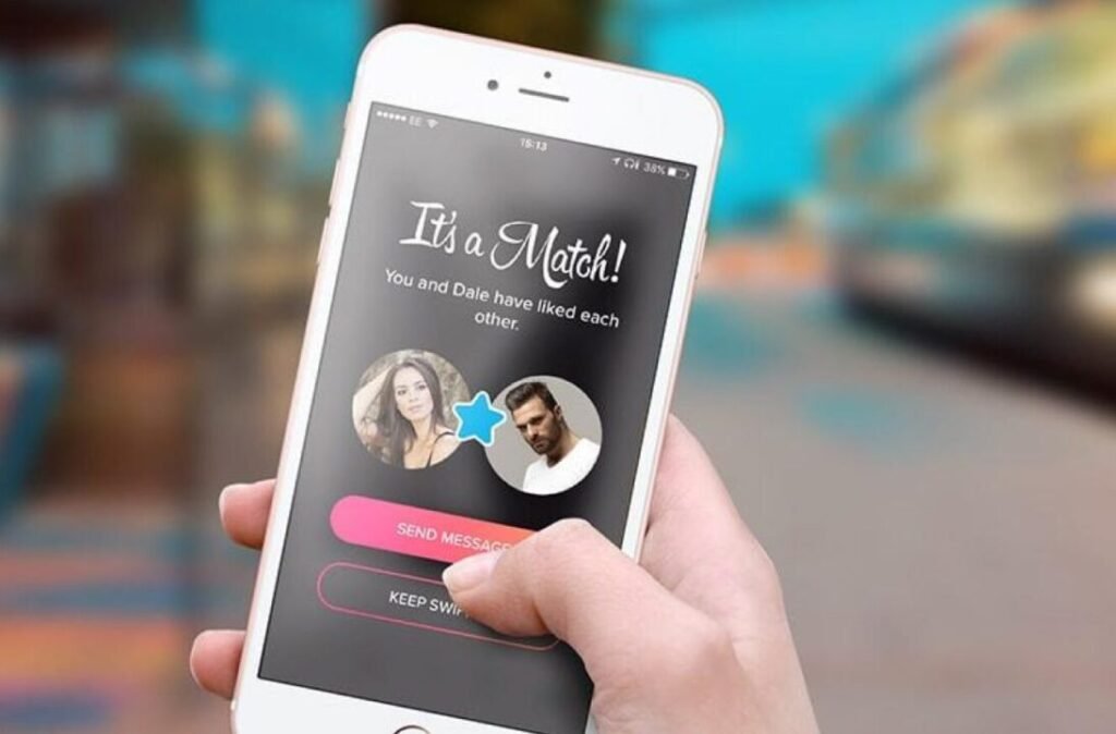 Person holding a smartphone displaying a dating app screen saying "It's a Match!" with photos and names of two people who have liked each other on the app.