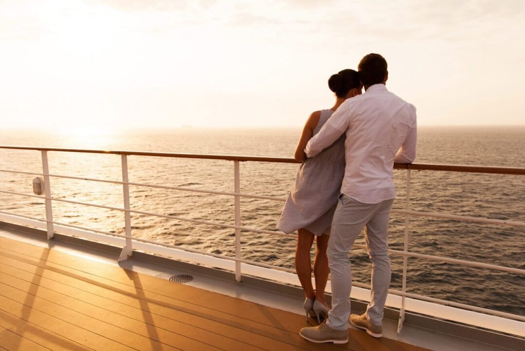 Romantic couple enjoys sunset view on cruise ship deck.