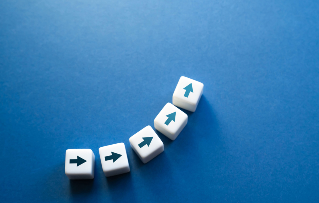 Five white dice with directional arrows on them, arranged diagonally on a blue background, with the first, third, and fifth die showing upward arrows and the second and fourth die showing rightward arrows.