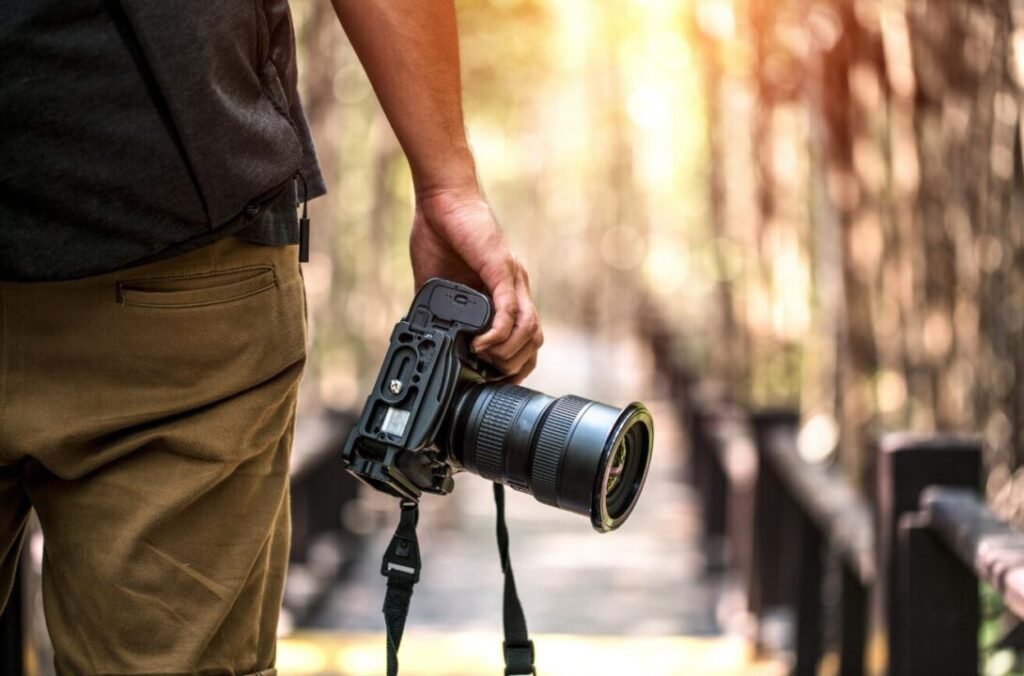 Photographer capturing golden hour light in forest with DSLR camera.