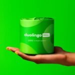 Duolingo ROLL Toilet Paper: Language Lovers Novelty in a Hand Against Green Background.